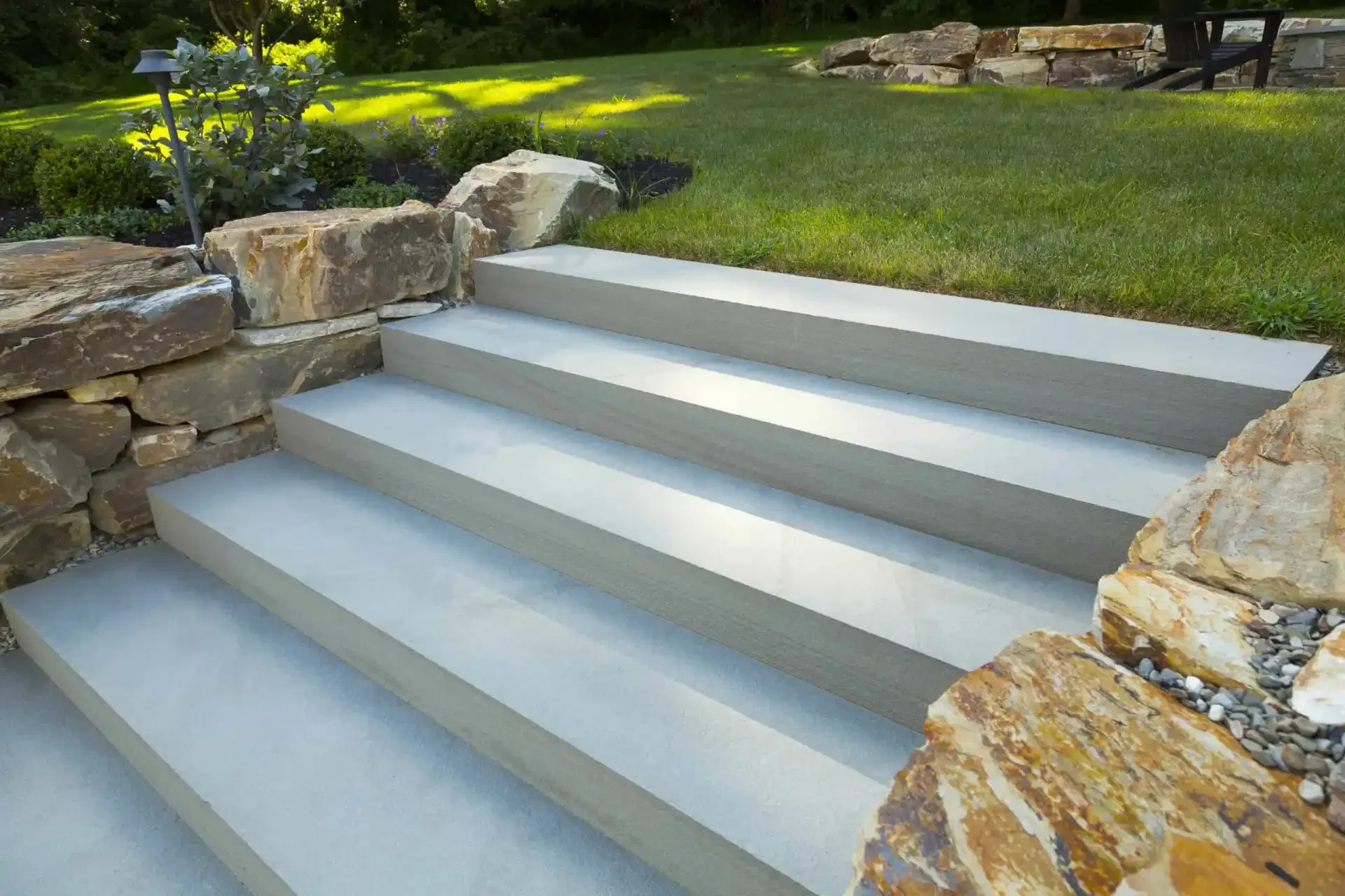 Bluestone step set with natural boulder walls and manicured lawn