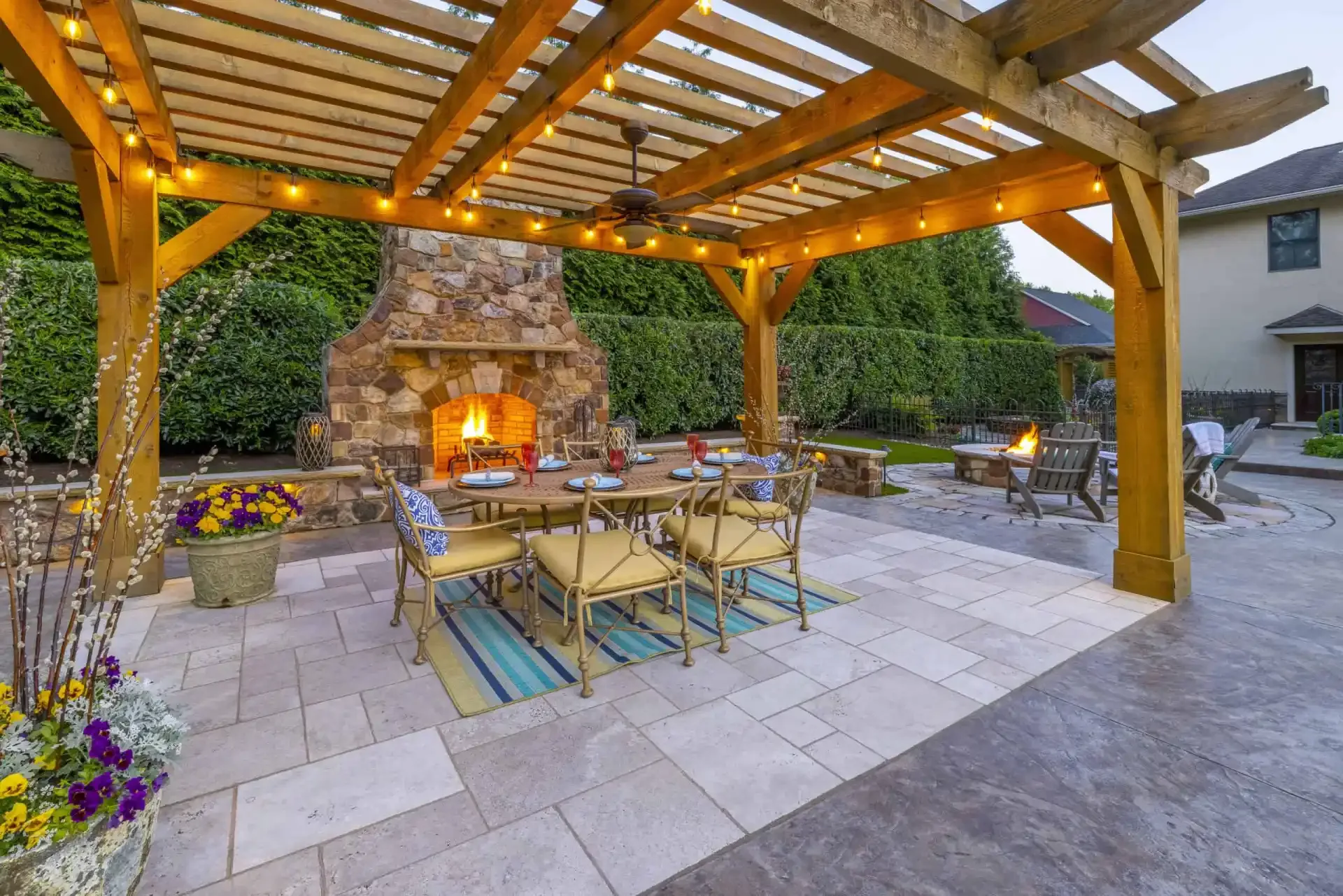 Custom timber pergola with stone fireplace and bluestone patio dining area built by DiSabatino in Delaware County, PA