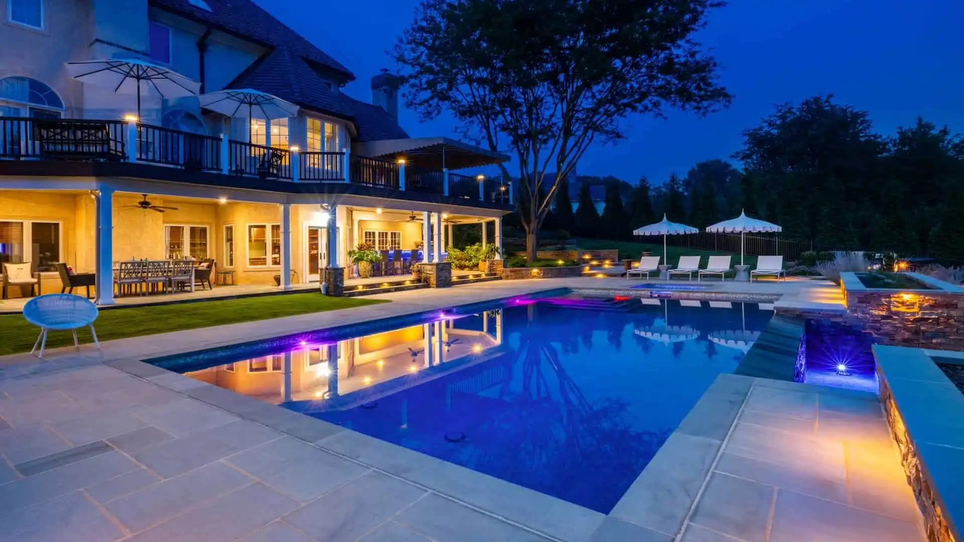 Luxury landscape design with layered plantings, lighting, and water feature