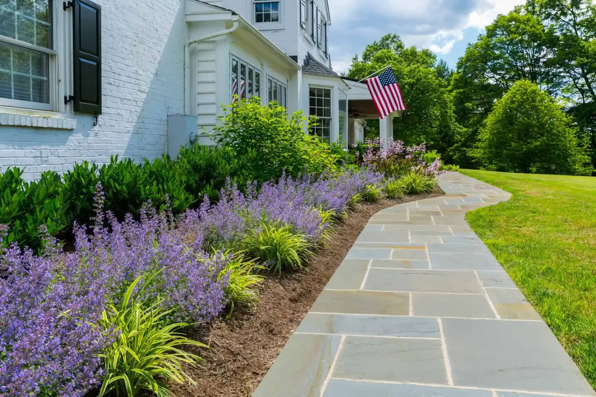 Bluestone walkway with layered perennial border and evergreen plantings