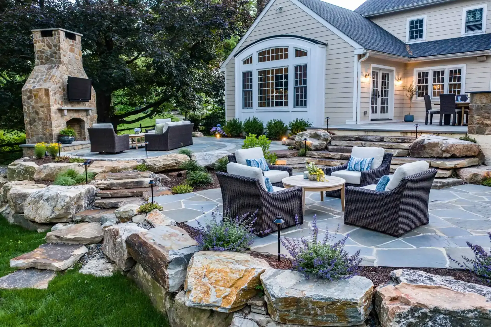 Flagstone patio with boulder retaining walls, lounge seating, and stone fireplace in Wilmington, DE
