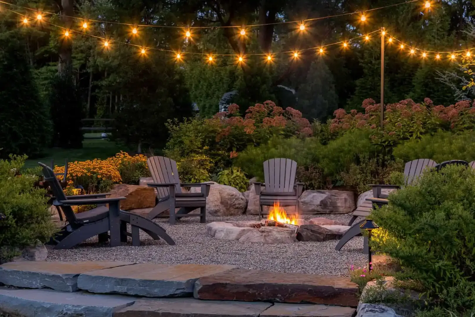 Evening fire pit patio with Adirondack seating and festoon lighting